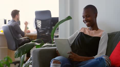 Vista-Frontal-De-Una-Joven-Empresaria-Negra-Sentada-En-El-Sofá-Y-Haciendo-Videollamadas-En-Una-Tableta-Digital-4k