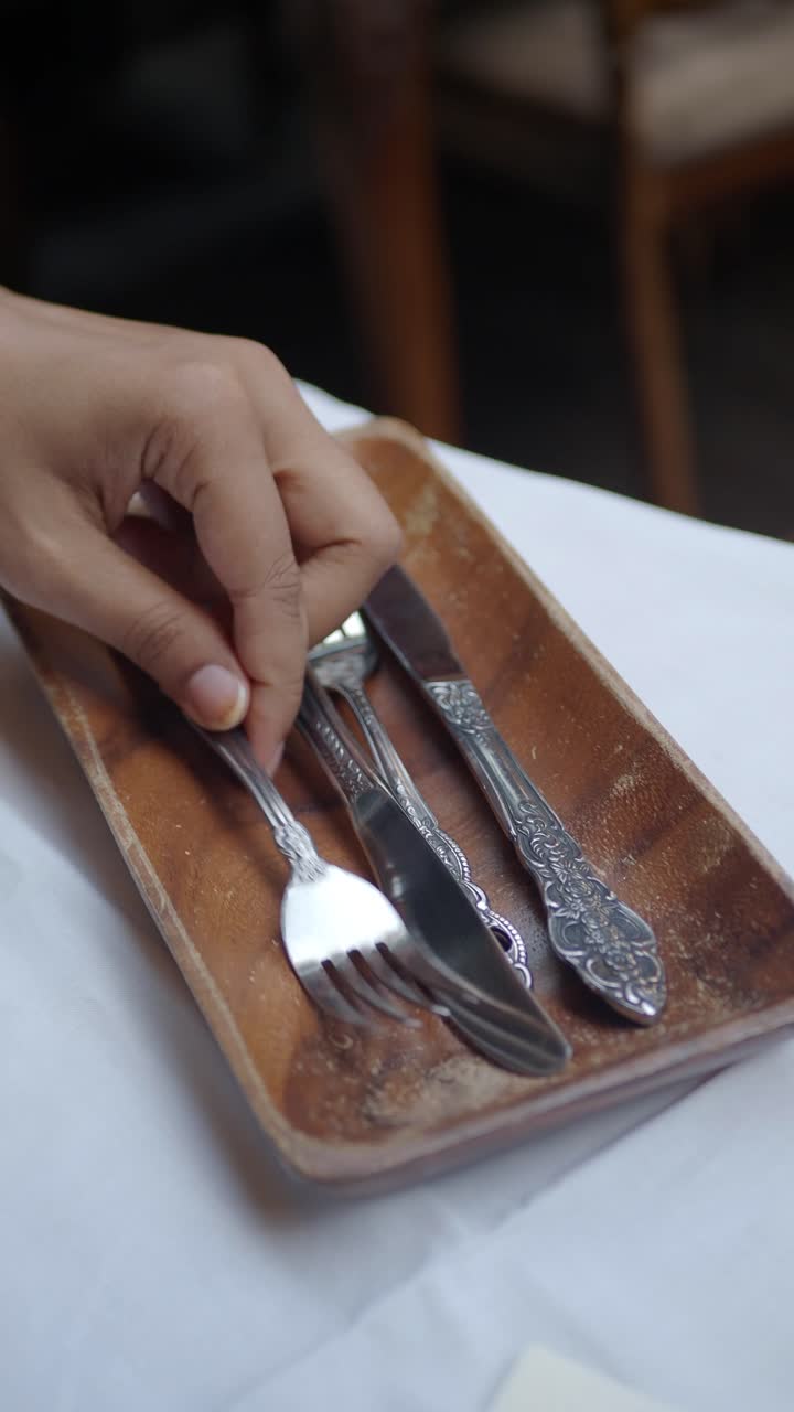 Hand Arranging Silverware on a Wooden Tray