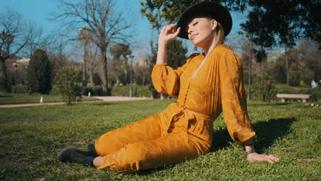 Stylish-young-woman-sitting-in-the-grass-outdoors.