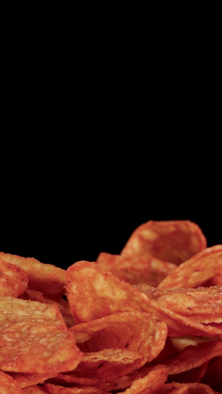 Croccanti tortilla chips per nachos cadono su una pila, ripresi al rallentatore su sfondo nero