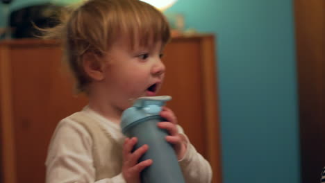 un lindo niño gordito bebiendo batido puesto en un recipiente azul mientras observa a sus padres a su lado - primer plano