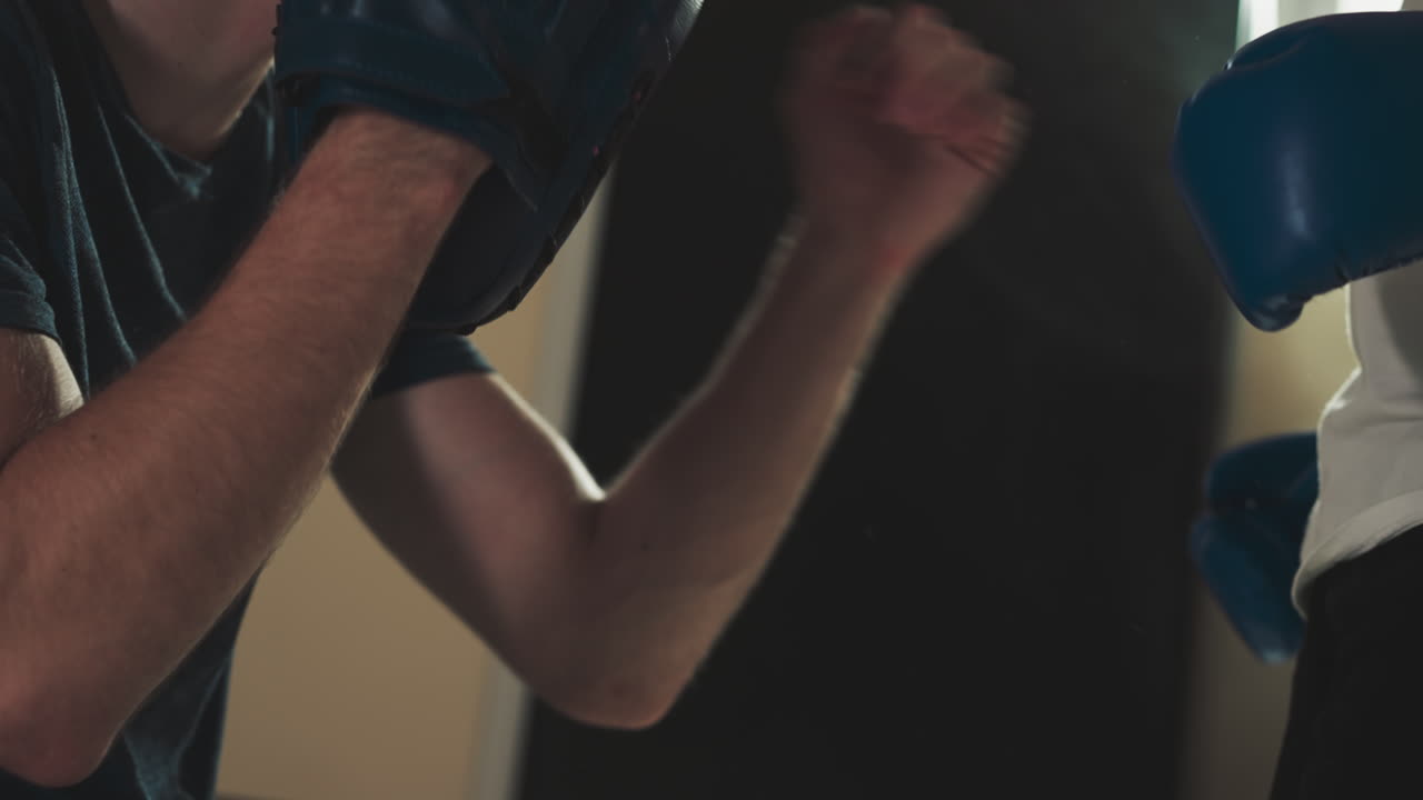 entrenador detiene a un niño pateando la almohadilla de la mano en el gimnasio. instructor profesional enseña al niño a luchar en el club de combate en cámara lenta. lección de kickboxing