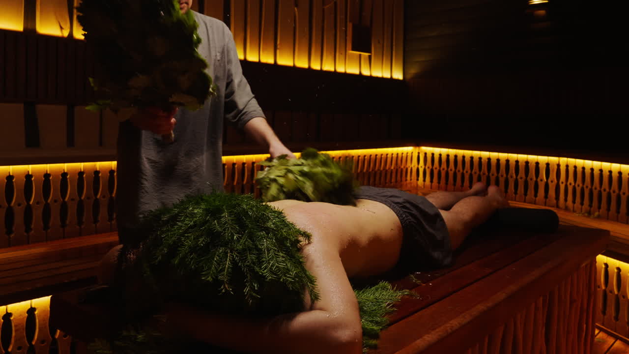Man receiving a traditional Russian banya treatment with herbal branches