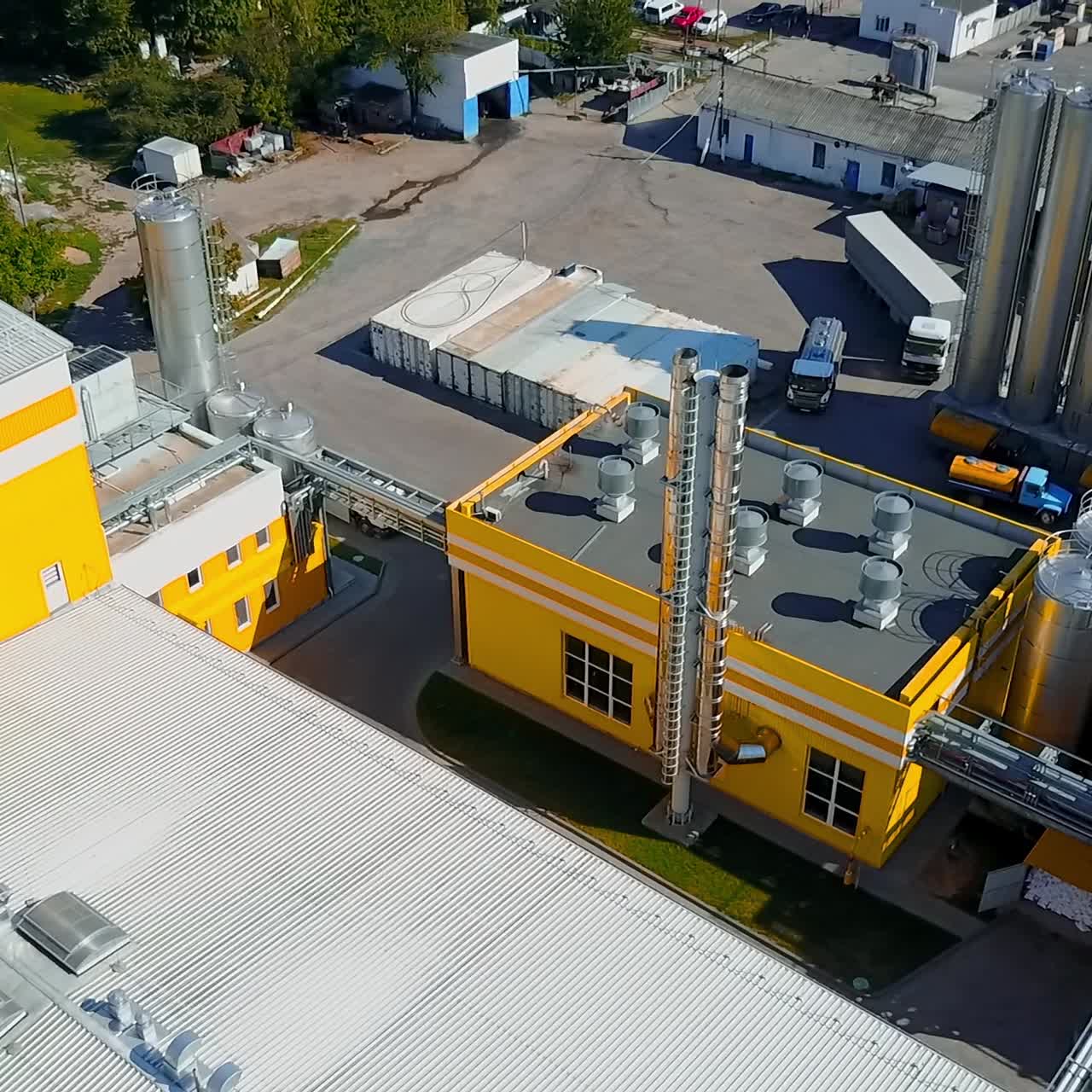 Grey lorry moving by the territory of the modern industrial plant. Premises of the factory on sunny day from aerial view