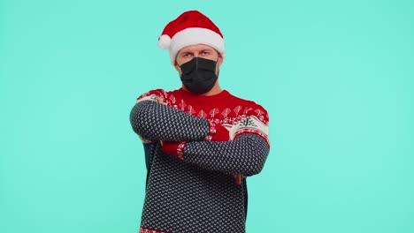 hombre con suéter rojo navideño con máscara facial ppe para protegerse del coronavirus en cuarentena de encierro