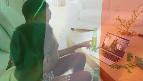 irish flag waving against couple waving while having video call on laptop at home