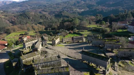 Elevated-granite-granaries-structures-cast-long-dark-shadows-on-ground,-Soajo-Portugal