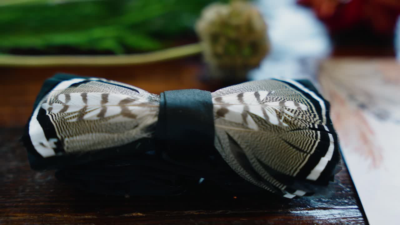Close-up rack focus shot of a unique duck feather bow tie, part of the groom’s wedding attire at a fall wedding in South Georgia.