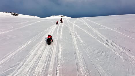 Aerial-view-over-people-riding-snowmobiles-on-the-icy-ground-of-Myrdalsjokull-glacier-in-Iceland