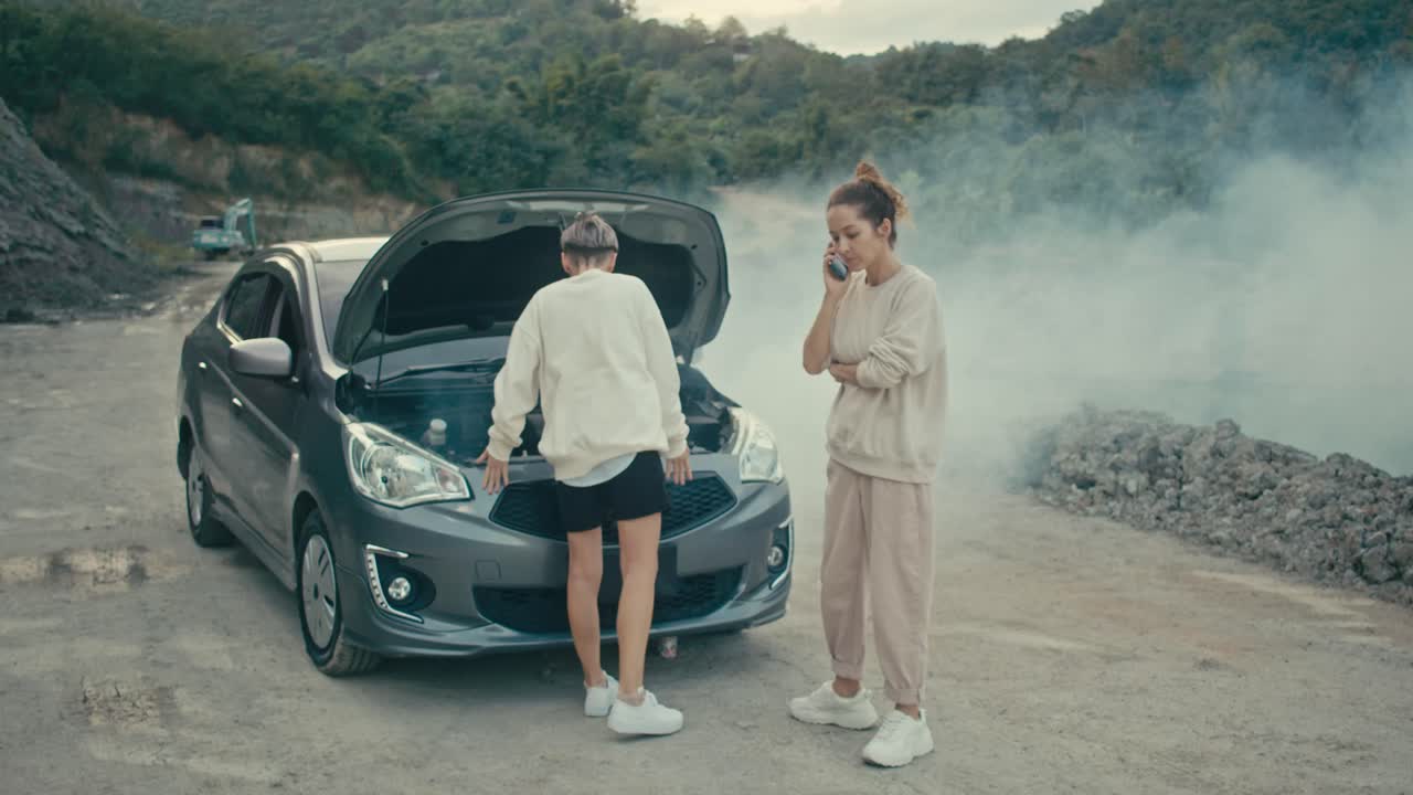 Two women deal with a broken down car on a rural road