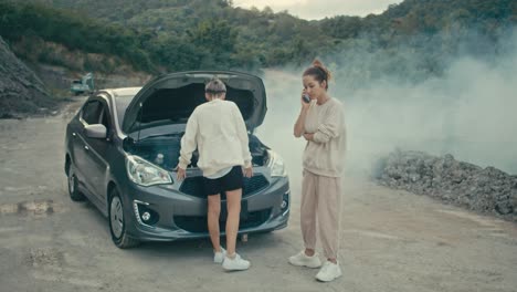 two women deal with a broken down car on a rural road