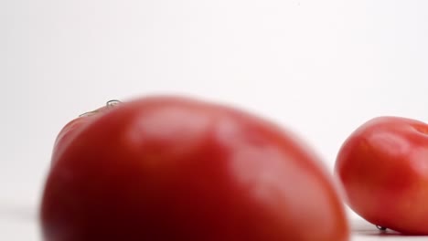 Fresh-bright-red-plump-tomatoes-bouncing-and-rolling-on-white-table-top-in-slow-motion