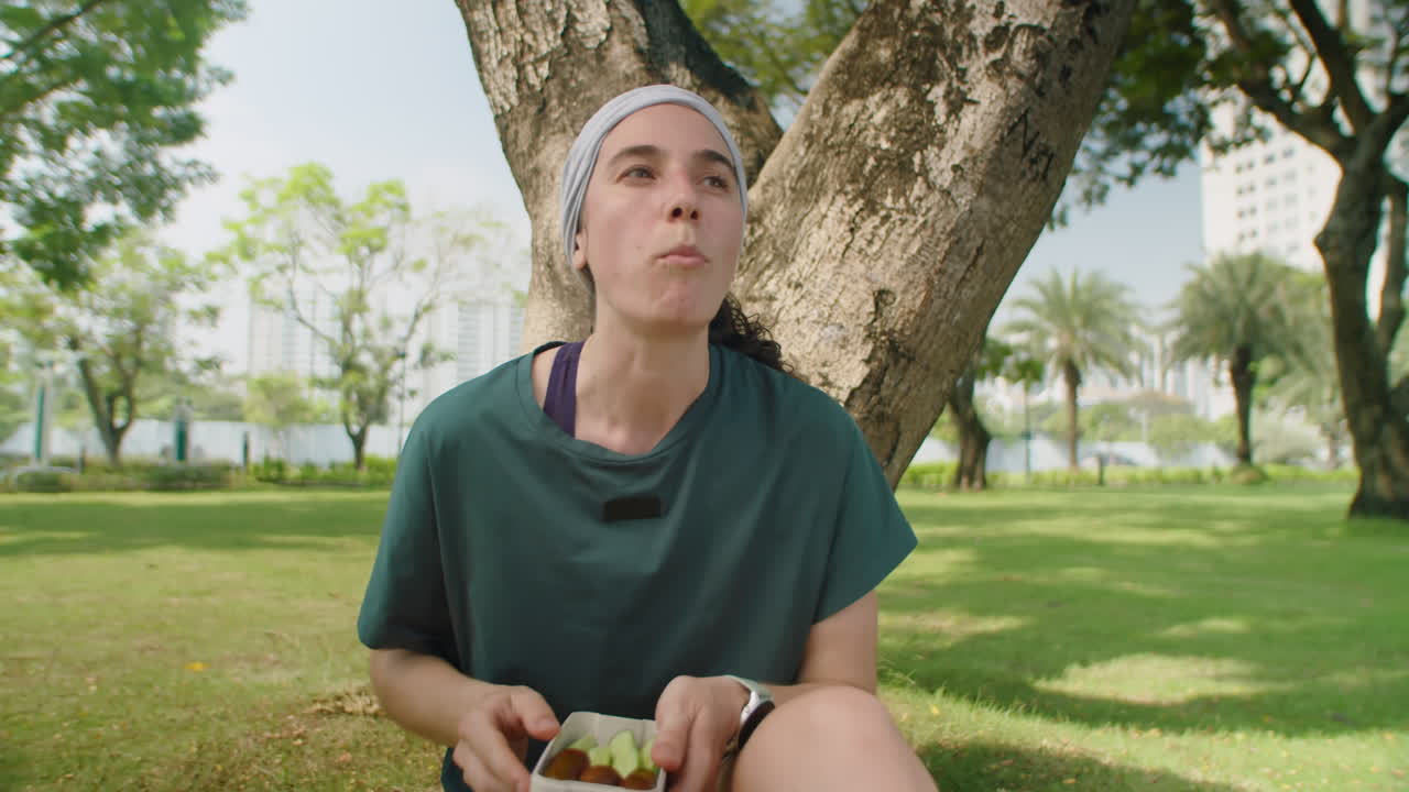 Woman Eating Veggies after Workout in Park