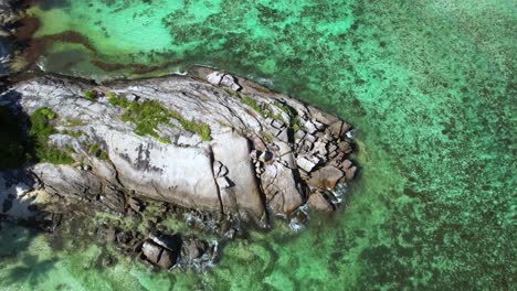 bird eye drone shot at anse forbans beach, people walking on huge granite rock mahe seychelles