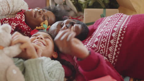 happy african american family lying on floor and playing on christmas