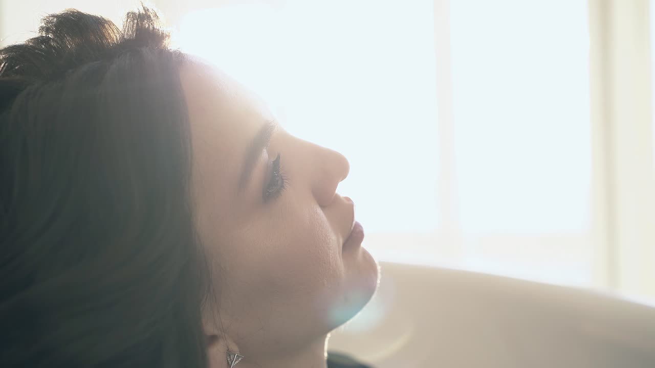 메이크업 을 한 예쁜 여인 이  ⁇ 빛 에 가까운 측면 시야 에서 휴식 하고 있다