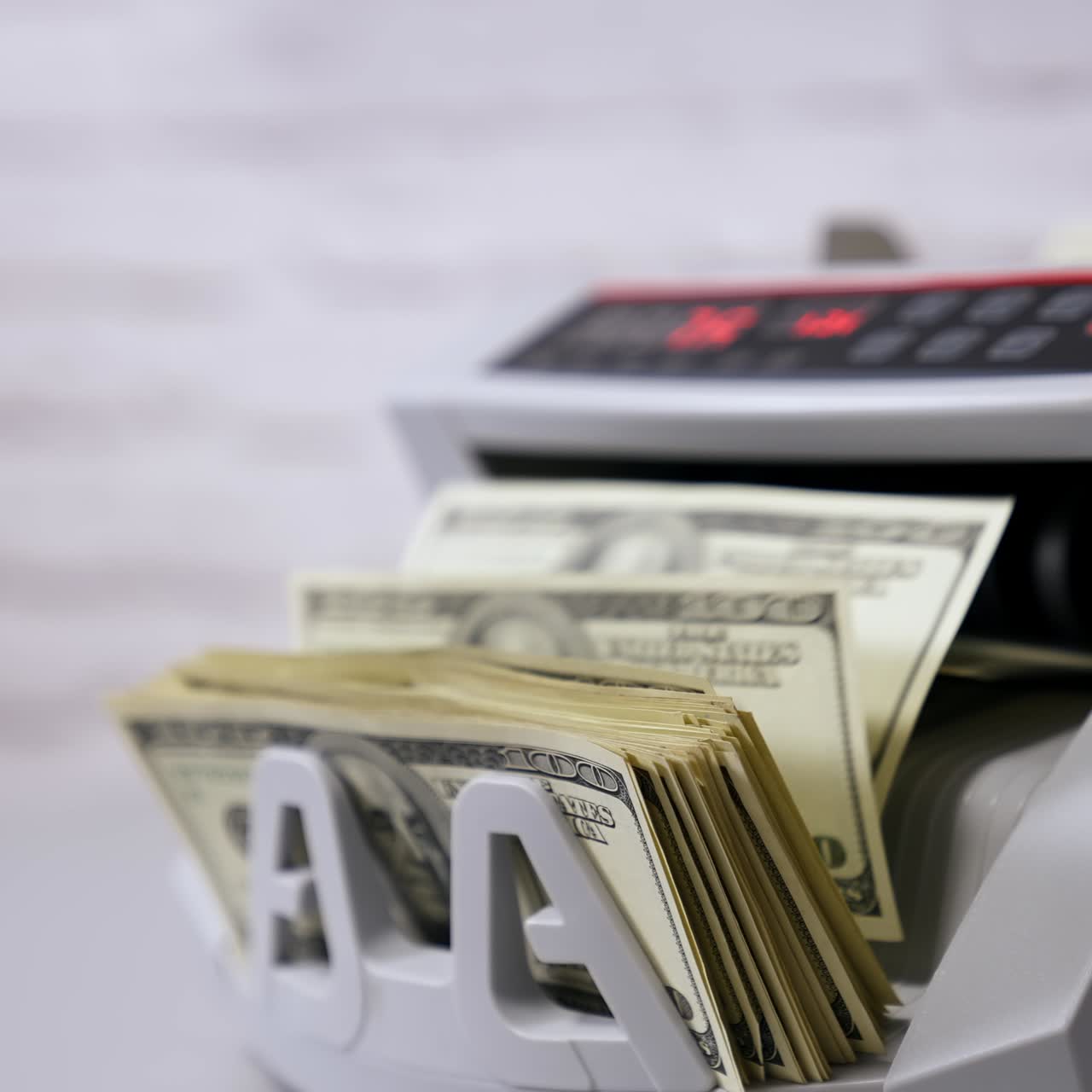 Impiegato che conta a mano i dollari con una macchina contabanote elettronica in un ufficio bancario o in un cambiavalute.