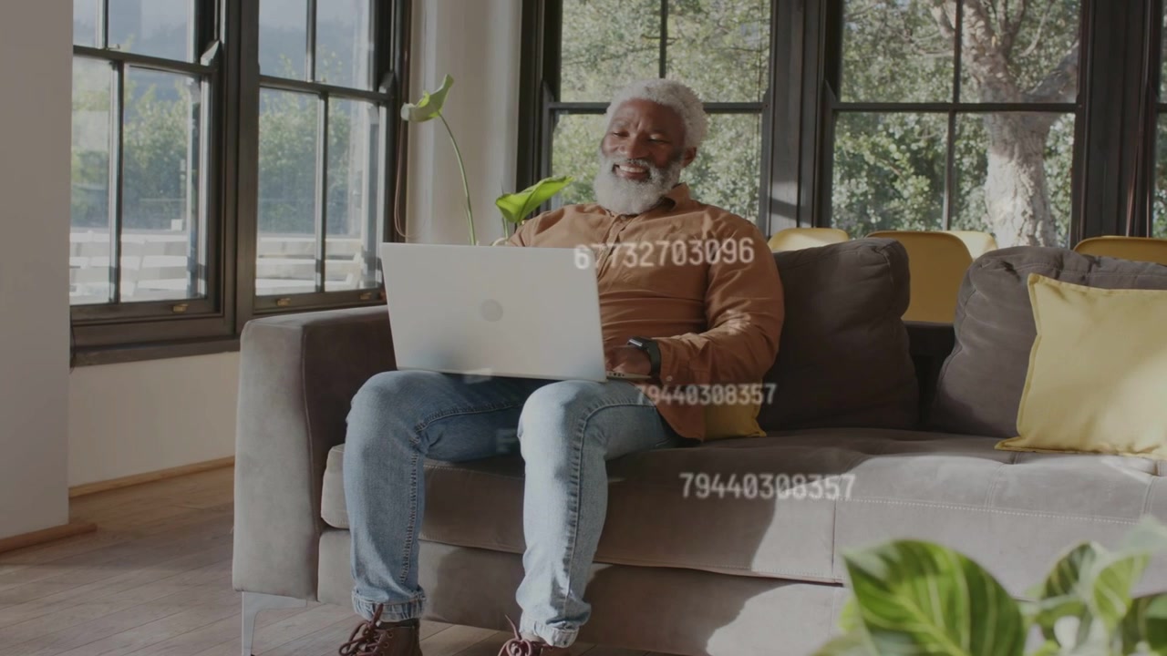 Senior man sitting on sofa typing on laptop, starting moving numeric overlays and reviewing finance