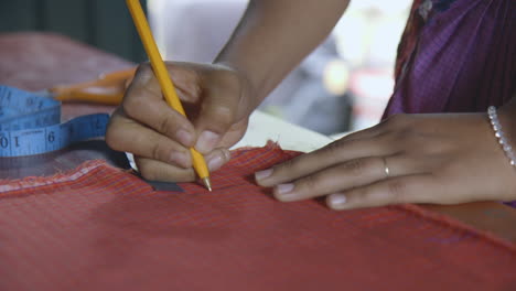 una mujer dibujando un diseño en una pieza de material