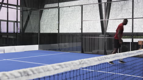 african american man playing padel tennis on indoor court, focused and ready