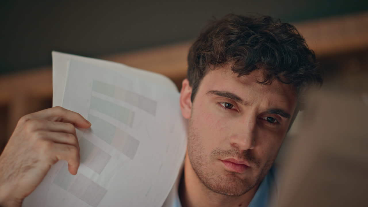 Primo piano di un finanziere che esamina documenti in un ufficio aziendale buio. Uomo d'affari serio.