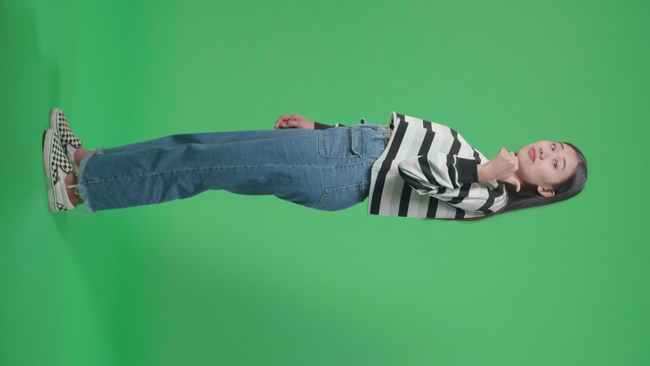 Woman giving thumbs up in casual outfit against green screen