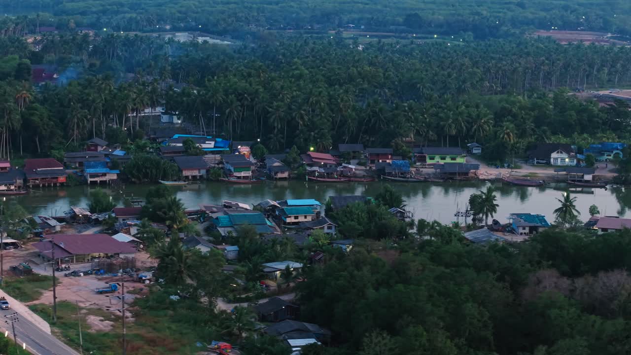 Aerial view of a tropical village on the riverbank at dusk