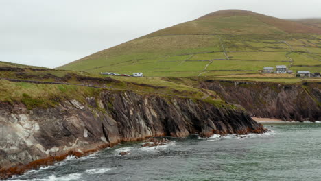 Bajo-Vuelo-Sobre-La-Superficie-Del-Agua-A-Lo-Largo-De-La-Costa-Del-Mar.-Pendiente-Rocosa-Escarpada-Que-Cae-Al-Agua.-Atracción-Turística-Con-Aparcamiento.-Irlanda