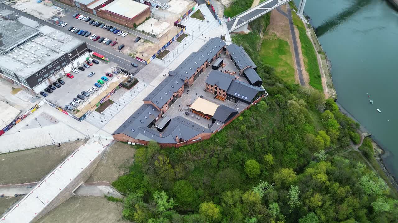 A forward drone shot flies over the Sheepfolds development in Sunderland, revealing the redeveloped courtyard buildings, riverside cliffs, the River Wear and the Keel Crossing footbridge beyond