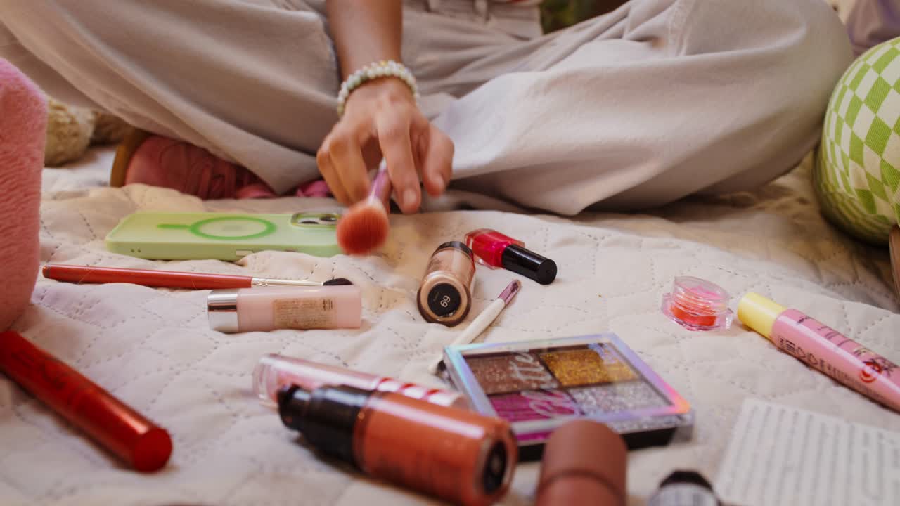 메이크업이 어져 있는 침대에 앉아 있는 여자