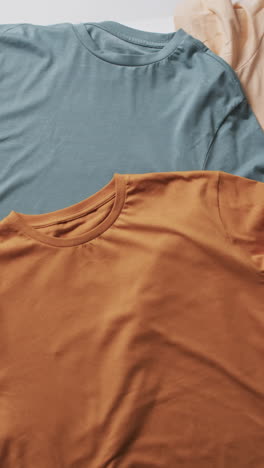 vertical video of multi coloured t shirts with copy space background