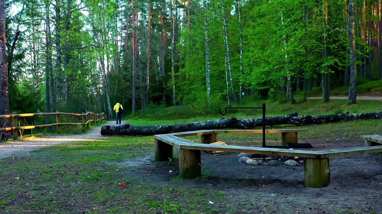 Forest picnic spot with circular bench and fire pit as person walks away in background