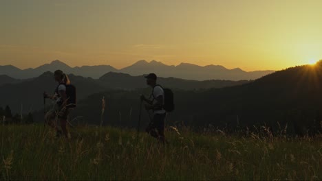 couple admiring a scenic mountain sunset before continuing their peaceful evening hike