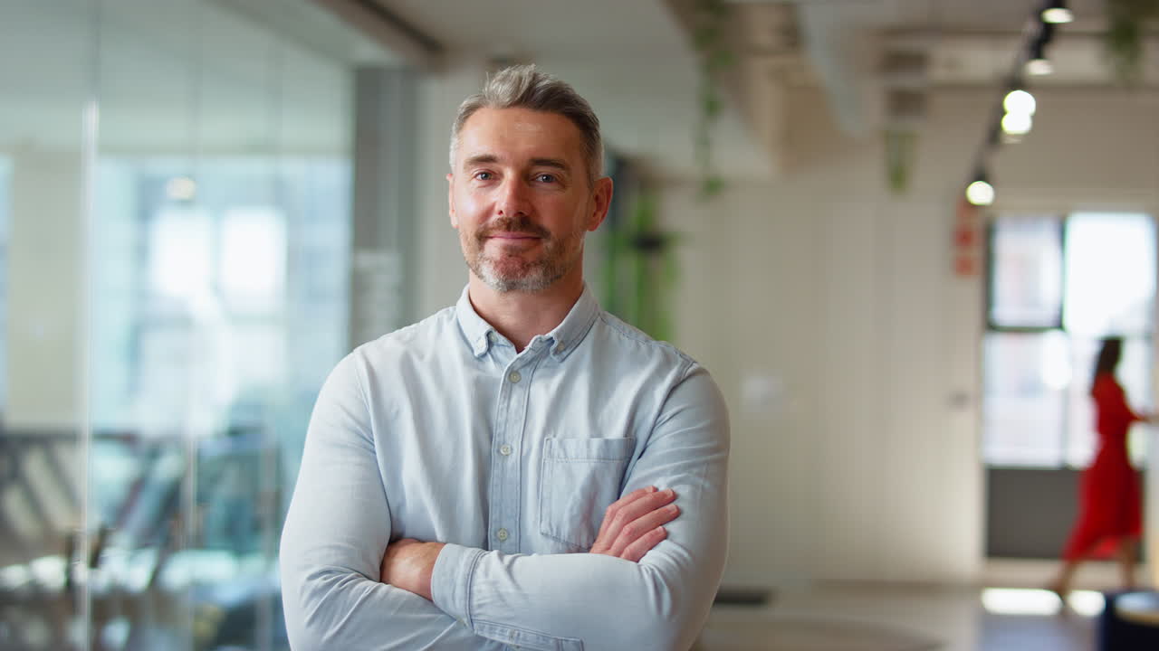 Portrait Of Serious Mature Businessman Standing In Modern Open Plan Office