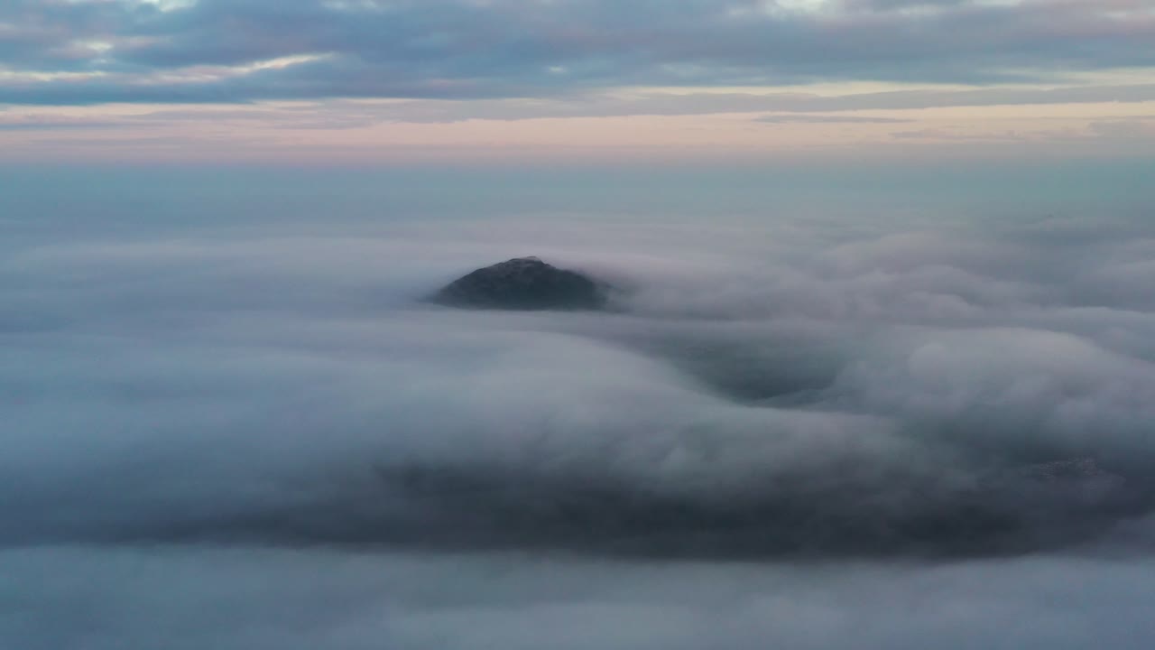 중국 홍콩 구룡봉의 흐린 푸른 시간에 빽빽한 구름층으로 거의 덮인 산 정상 위의 공중 궤도