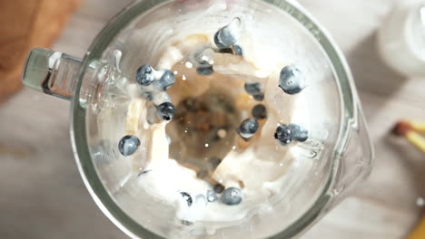 blueberry and banana milkshake mixed in a glass blender in slow motion, top view, inside of the device