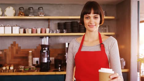 smiling waitress offering cup of coffee at counter