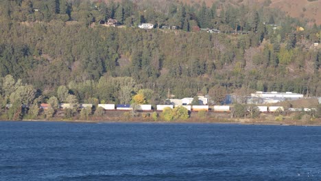 Vagones-De-Tren-De-Carga-Circulan-Por-La-Orilla-Del-Río-Columbia-Cerca-Del-Río-Hood,-Ee.uu.