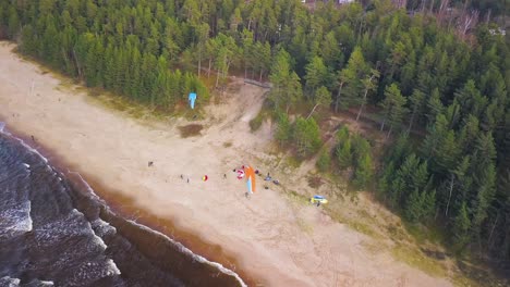 Touristen-Beobachten-Parasailing-An-Der-Küste-Mit-Ruhigen-Wellen,-Die-Das-Ufer-Erreichen