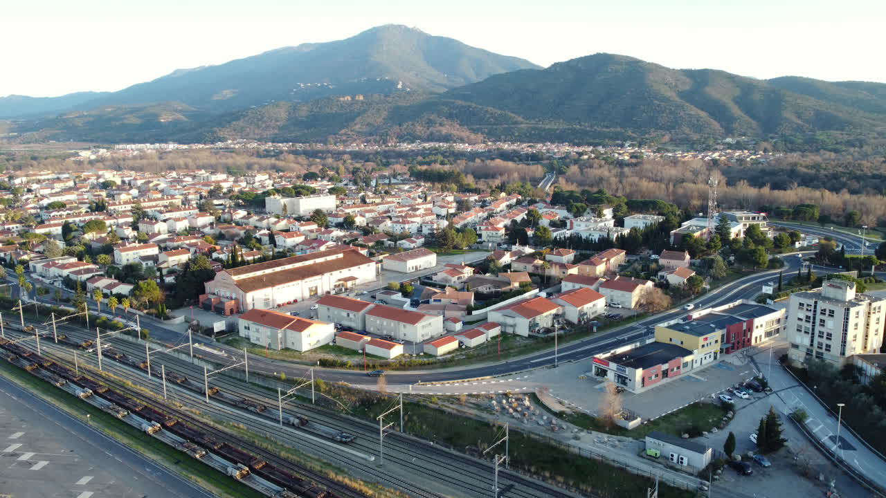 Aerial view of a French town with train tracks and mountains in the background
