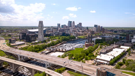 Drone-hyperlapse-view-of-I-35W-Saint-Anthony-Falls-Bridge-traffic-over-strong-flowing-Mississipppi-River-and-Minneapolis-skyline-in-background