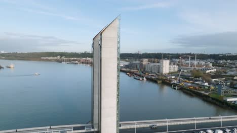 Jacques-Chaban-Delmas-lift-bridge-towers-with-car-traffic-crossing-the-Garonne-River-in-Bordeaux-France,-Aerial-parabolic-looking-down-shot