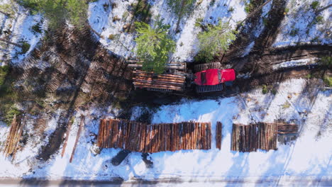 Forwarder-Mit-Greiferlader-Transportiert-Gefällte-Stämme-Entlang-Schneebedeckter-Strecke,-Luftaufnahme