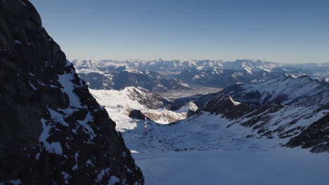 drone flying close to mountain tilting down revealing snowy mountain scenery on sunny winter day in austria