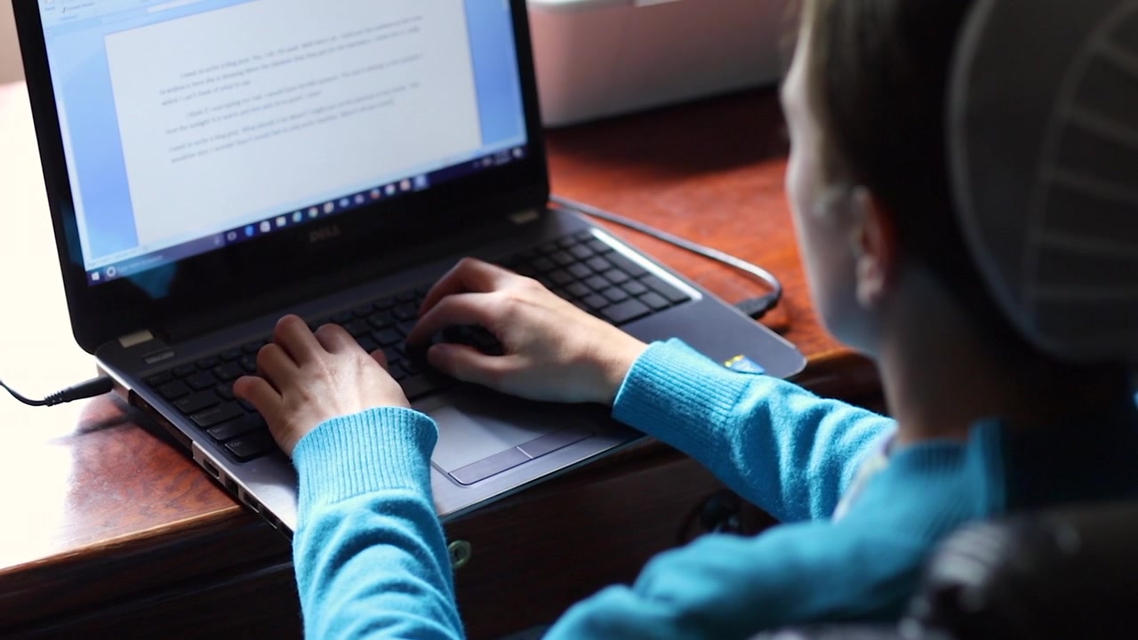 Un'inquadratura delle mani di una donna mennonita mentre digita su un computer portatile al rallentatore