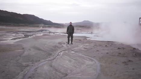 man standing in geothermal valley in mountains