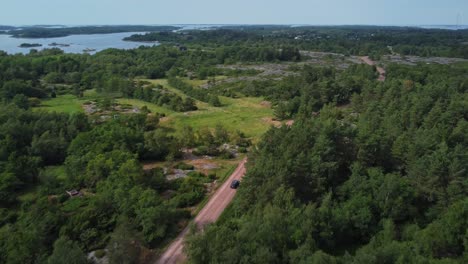 car driving in brando island in the middle of woods in aland islands, finland, aerial following shot