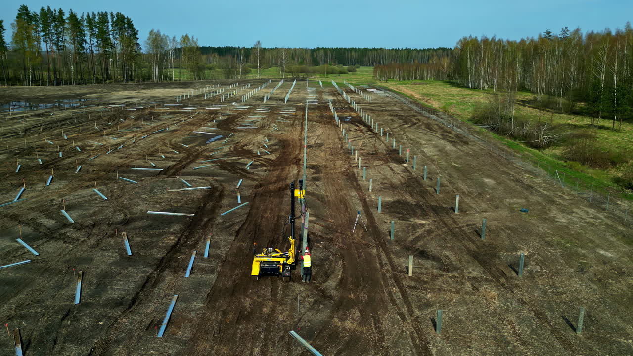 Luftfoto af et fungerende solcellepælemaskineri på markerne