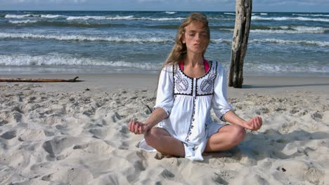 young woman meditating on the beach in the yoga lotus position.