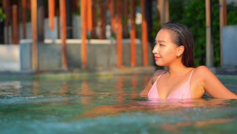 hot asian woman wearing bikini relaxing in the tropical luxury hotel spa pool outdoor